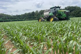 A John Deere sprayer in a field of corn