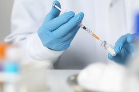 doctor in lab filling syringe with vaccine